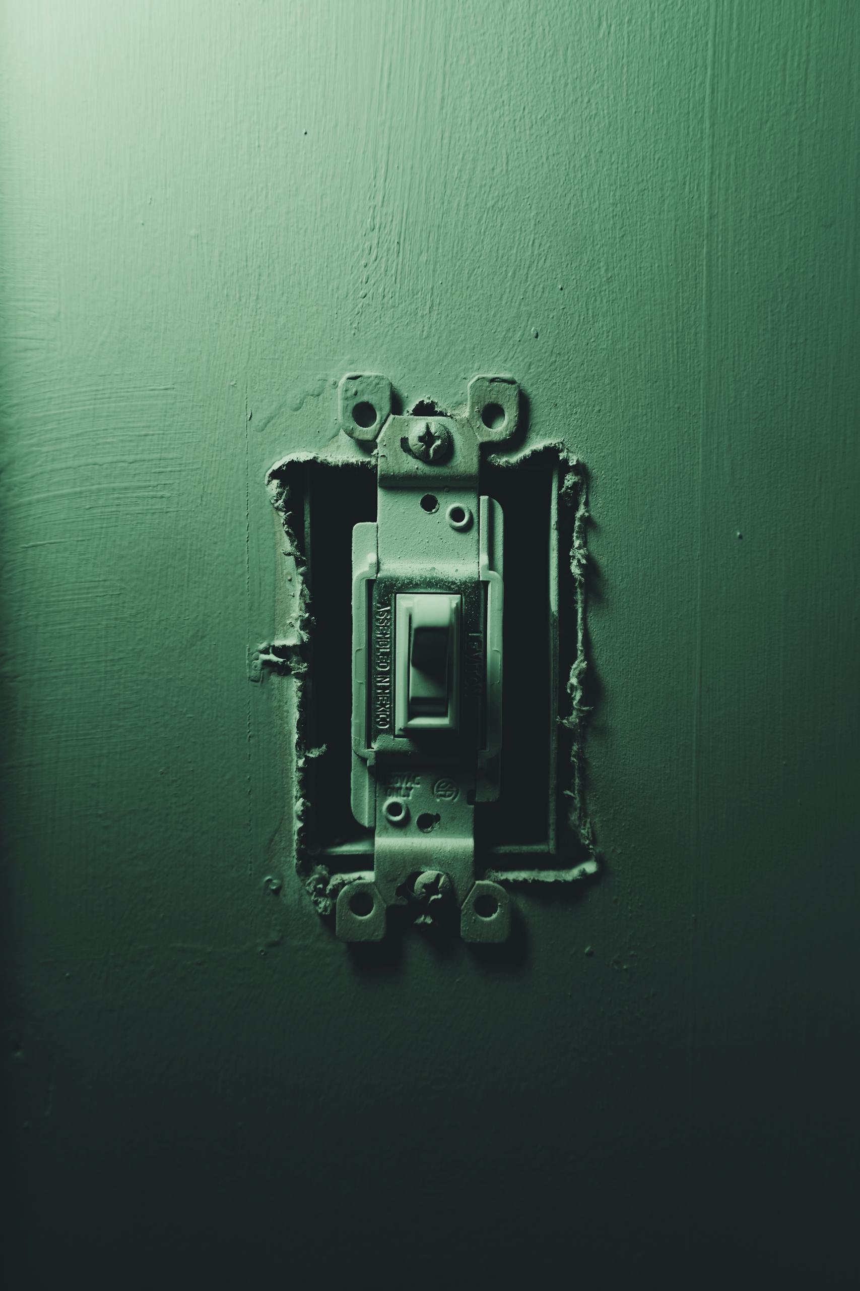 Detailed focus on an old light switch against a dark background, showcasing age and wear.